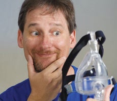 man holding a cpap mask with a skeptical expression