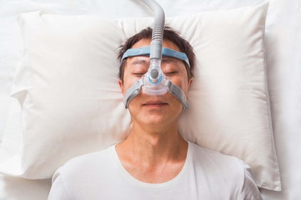 an asian man wearing a nasal cpap mask while sleeping in bed