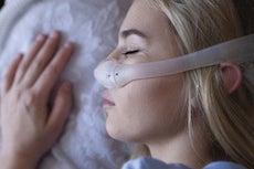 a woman sleeping on her side with a dreamwear nasal pillow mask