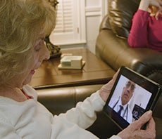Elderly woman at home telecommunicating with doctor on ipad