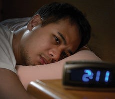 man struggling to sleep with clock reading 2:11